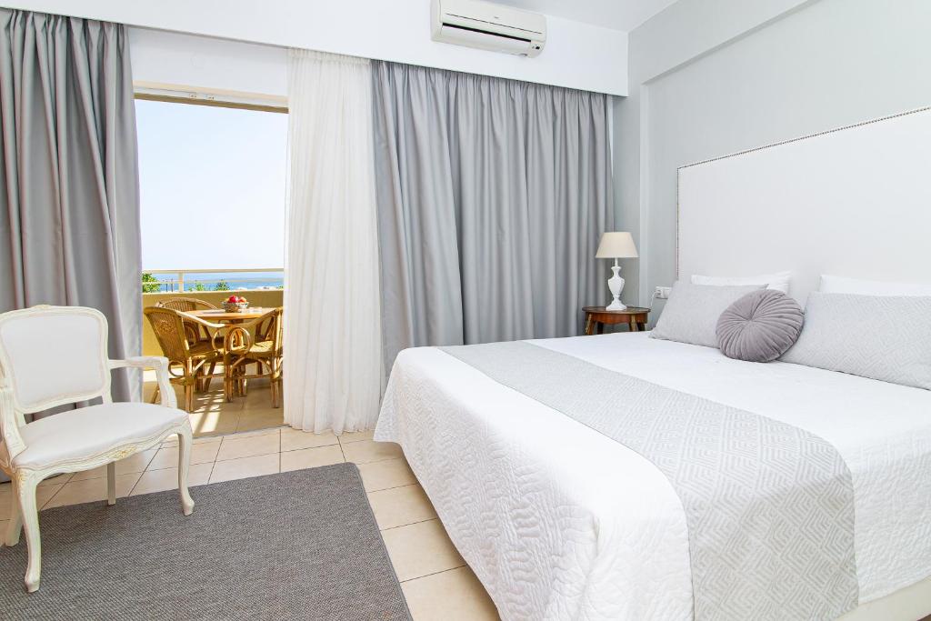 a bedroom with a white bed and a table and chairs at Villa Mare Monte ApartHotel in Malia