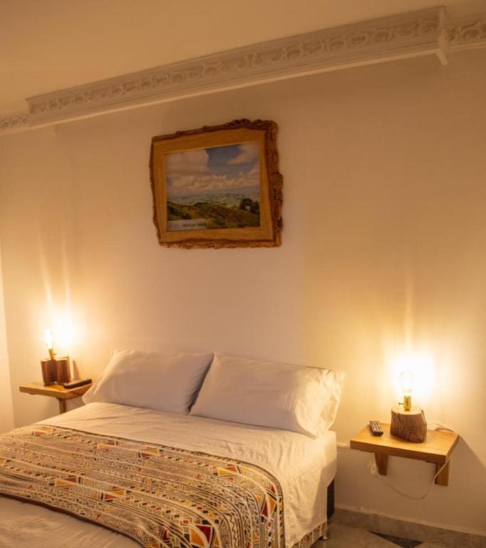 a bedroom with a bed and two lamps on tables at NOGAL HOSTEL in Pereira