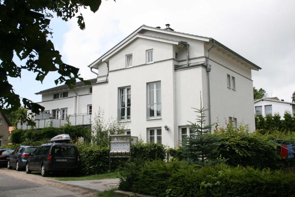 ein weißes Haus mit davor geparkt in der Unterkunft Zinnowitz Haus Isabella Wohnung 8 W8IZ in Zinnowitz