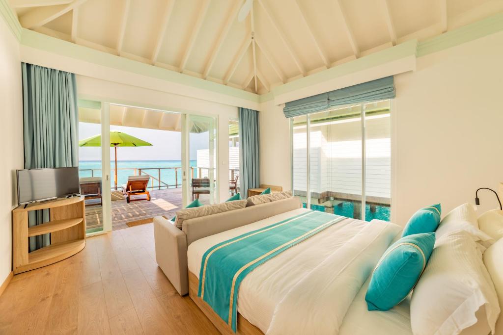 a bedroom with a bed and a view of the ocean at Siyam World Maldives - 24-Hour Premium All-inclusive with Free Transfer in Dhigurah