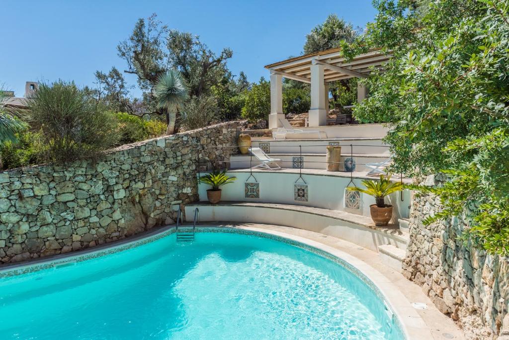 a swimming pool with a stone retaining wall and a stone staircase at Il Trullo - Tia Maria Country Inn in Racale