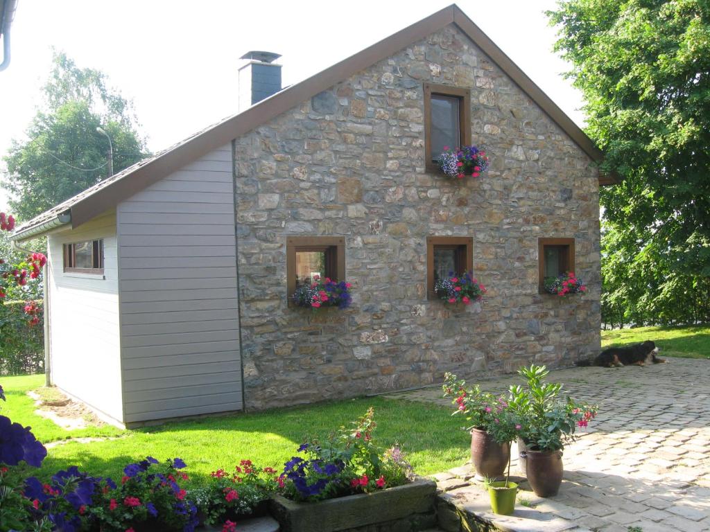 uma casa de pedra com flores em frente em Le Fournil d Andrimont em Stoumont