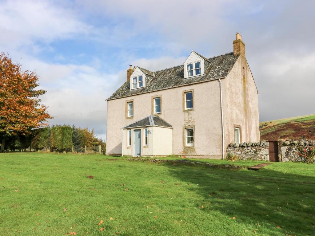 una casa vieja en un campo con un patio de césped en St Agnes, en Duns