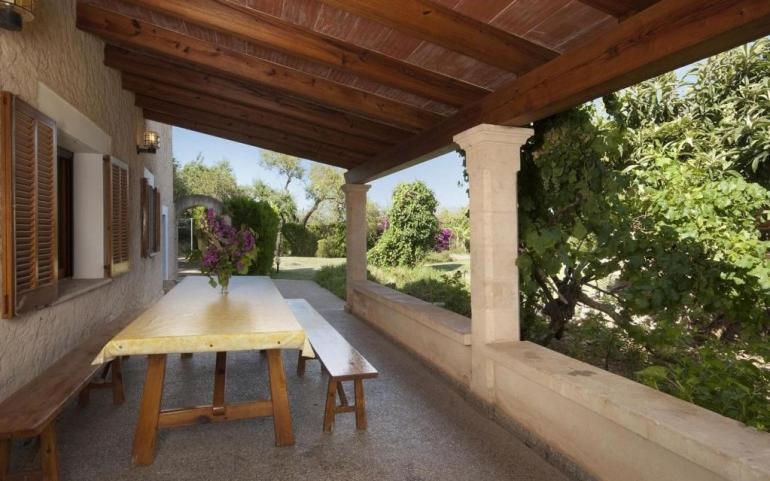 un tavolo in legno e una panca sul portico di una casa di Gran Villa en Pollensa a Pollença