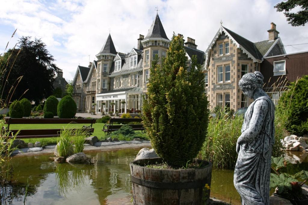 uma estátua em frente a um lago em frente a uma mansão em Craiglynne Hotel em Grantown-on-Spey