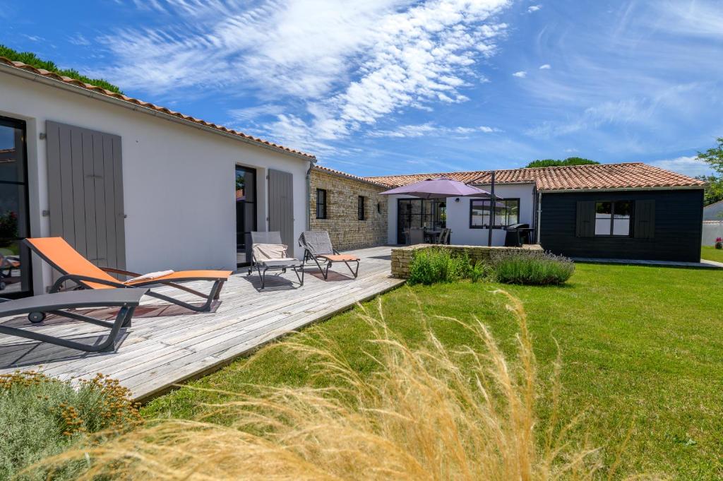 une terrasse en bois avec des chaises et une maison dans l'établissement La Cabane du pêcheur, à La Couarde-sur-Mer