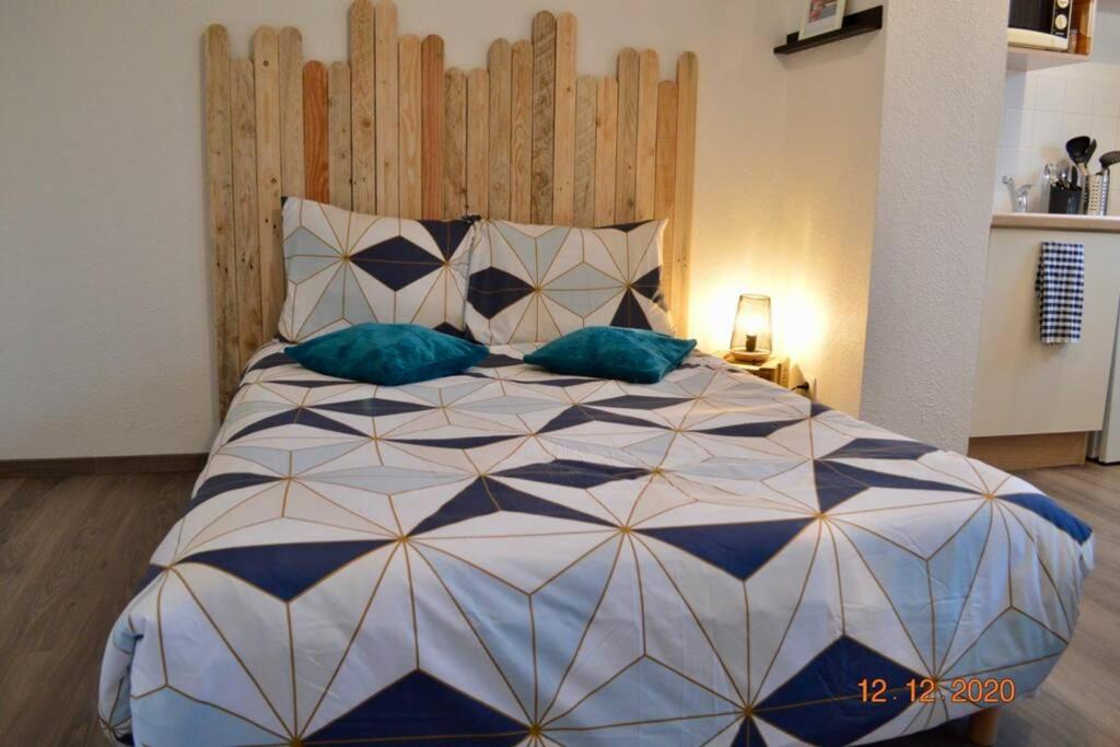 1 dormitorio con 1 cama grande con almohadas azules en Résidence les hauts de Honfleur, en Équemauville