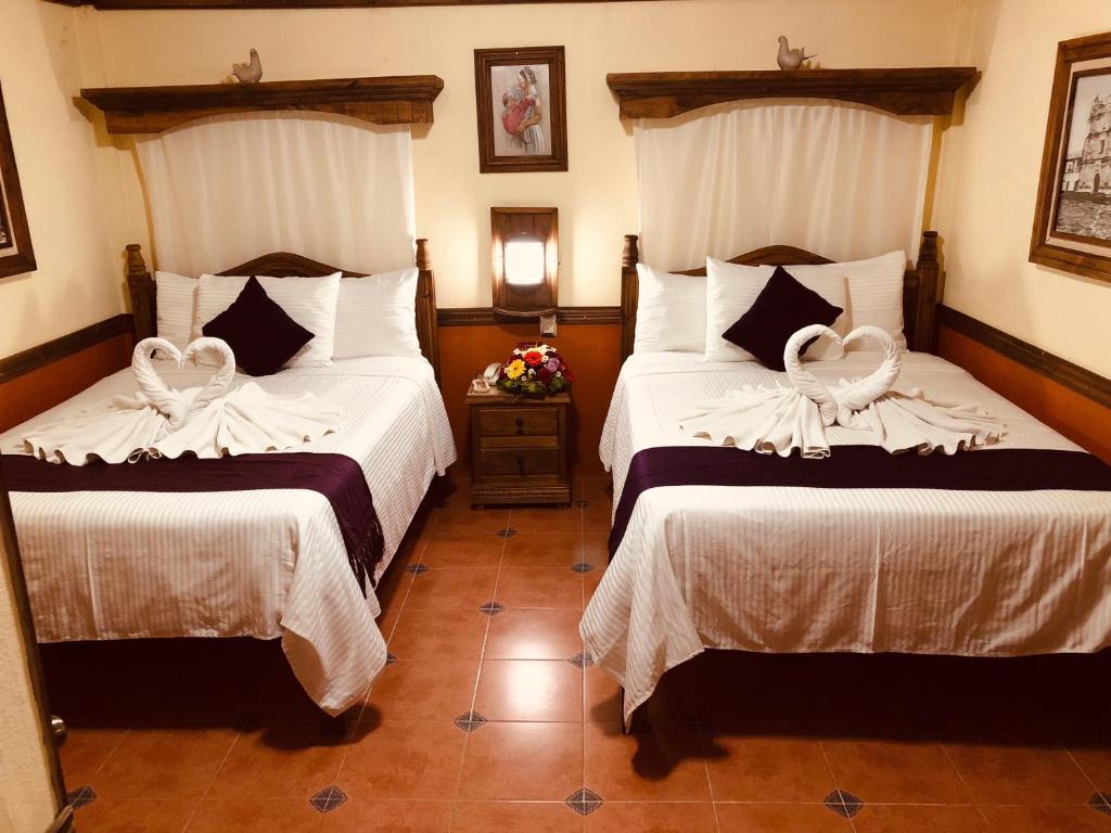 a hotel room with two beds with white covers at Hotel Tradicional in San Cristóbal de Las Casas