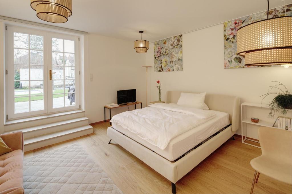 a white bedroom with a bed and a window at Boutique Apartments Freiburg - Eva in Freiburg im Breisgau