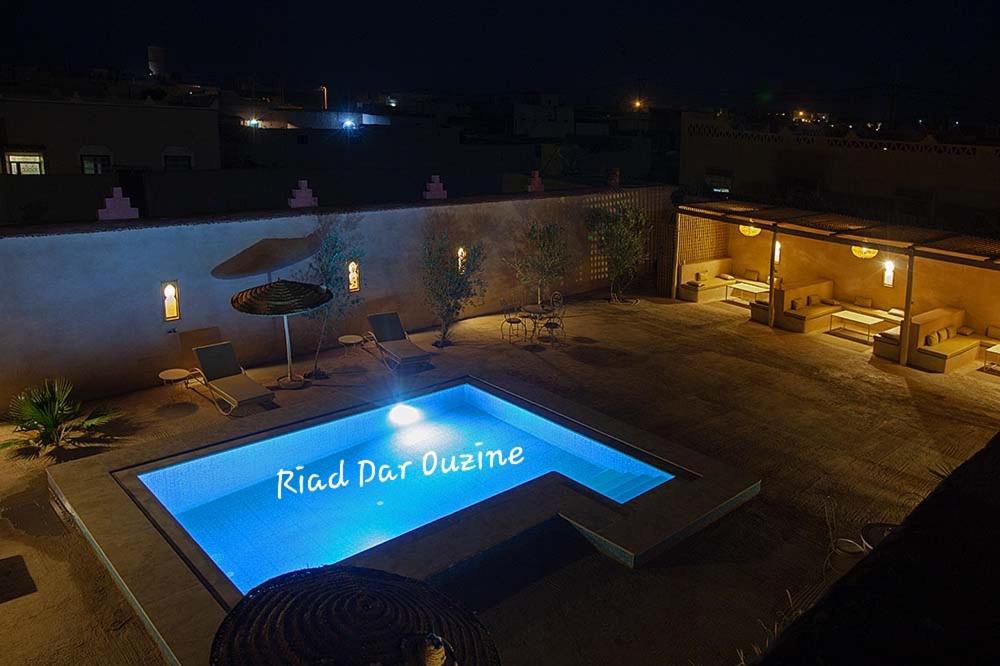 a swimming pool in a backyard at night at Riad Ouzine Merzouga in Merzouga