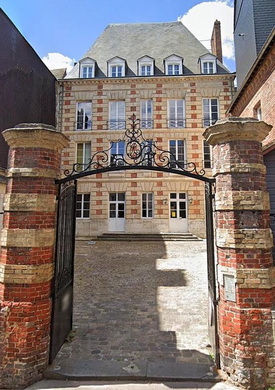 un accès à un grand bâtiment en briques avec une porte dans l'établissement Studio Louis XIII, à Rouen