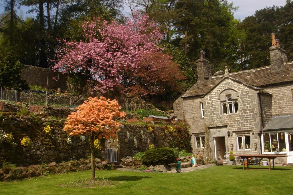 ein altes Steinhaus mit einem Baum im Hof in der Unterkunft Littlebank Country House in Settle