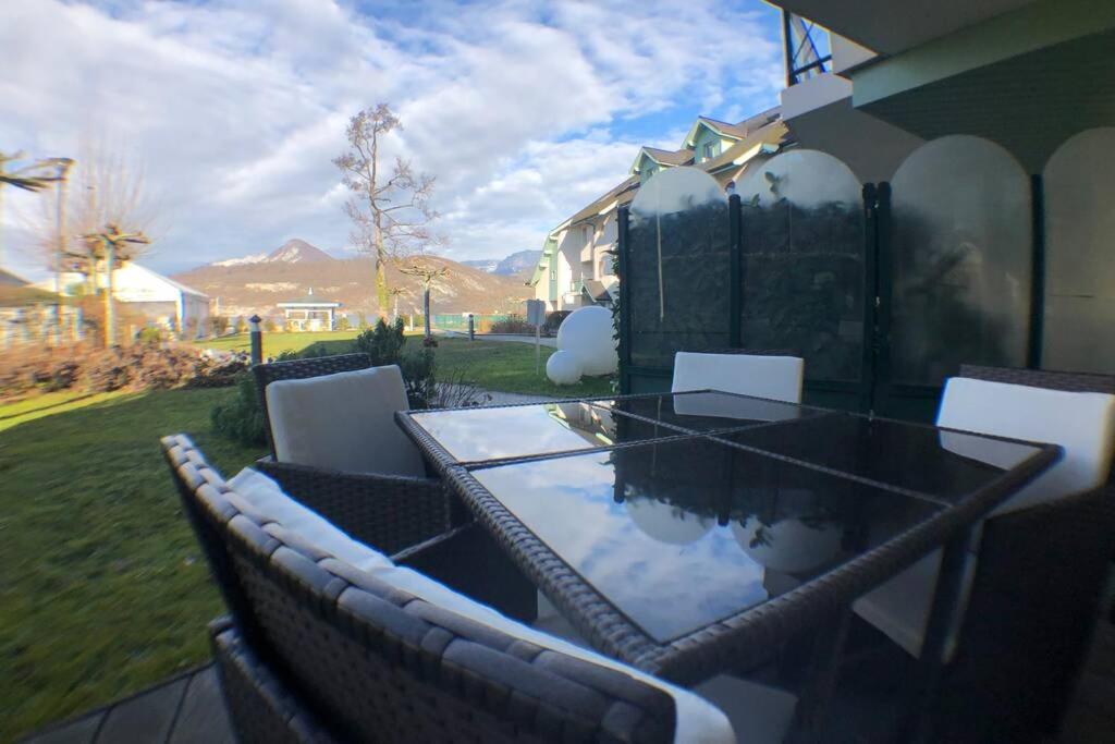 une table et des chaises en verre sur la terrasse dans l'établissement Rare : au bord du lac d’Annecy, cosy appartement en rez de jardin avec terrasse privative, à Duingt