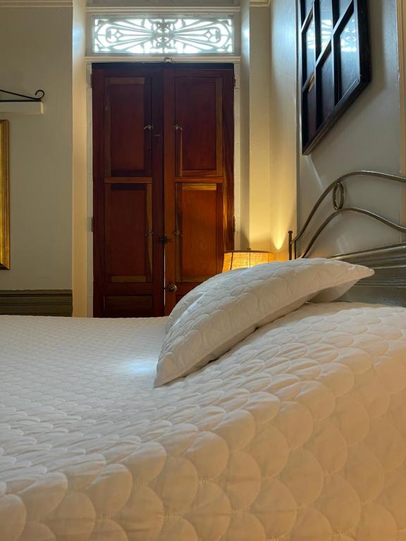 a bed in a bedroom with a white bedspread at Boutique Hotel Belgica in Ponce