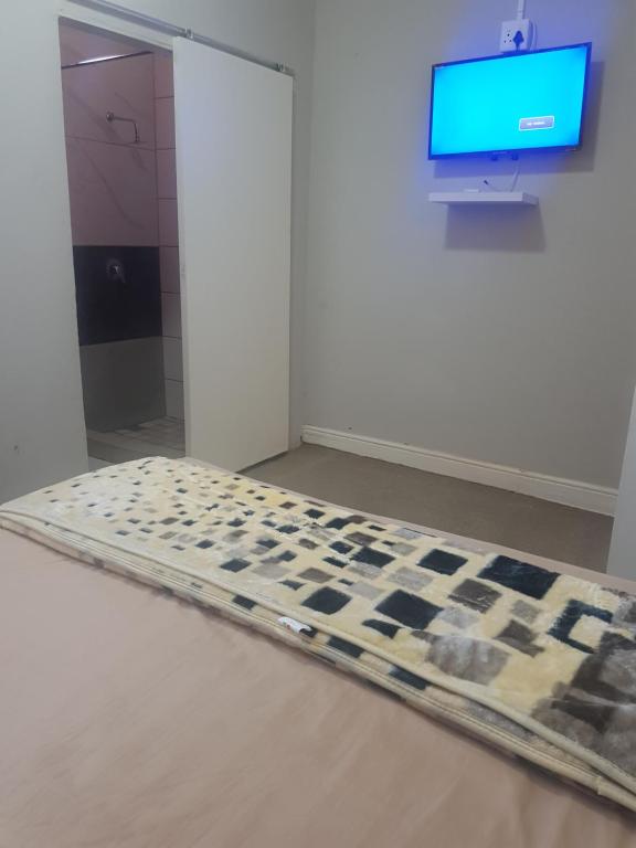 um quarto com uma cama de xadrez em frente a uma televisão em SALAMA LODGE em Cidade do Cabo