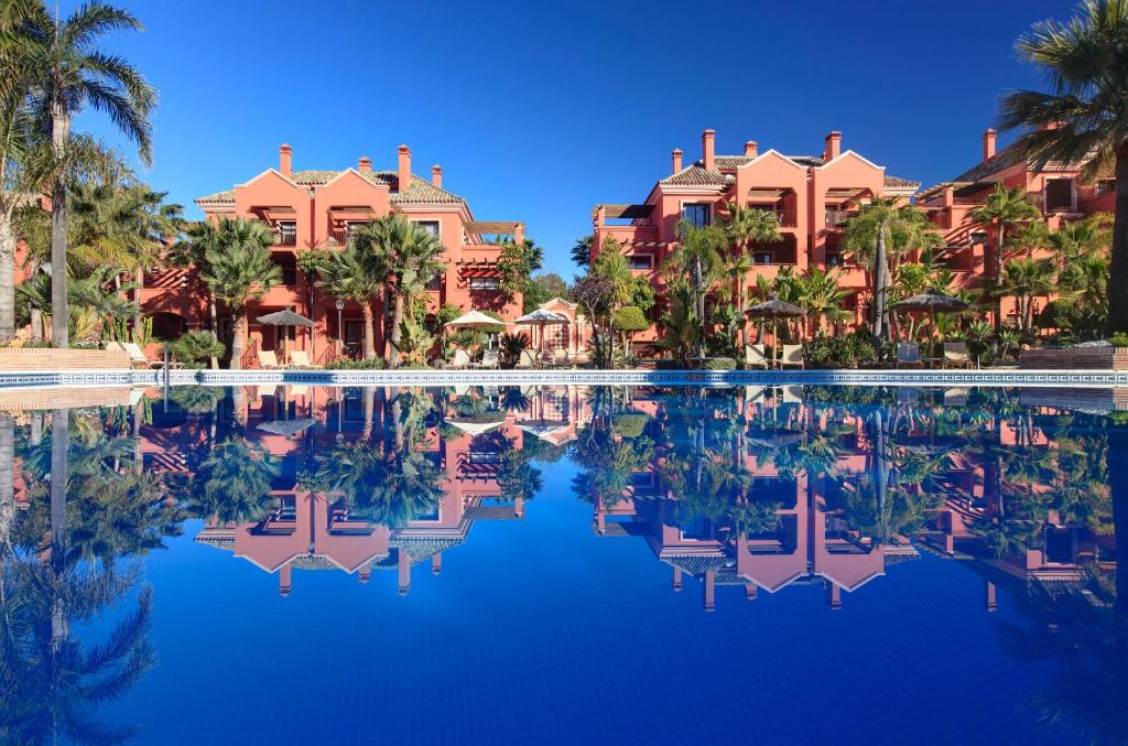 una piscina en un complejo con palmeras y casas en Vasari Resort, en Marbella