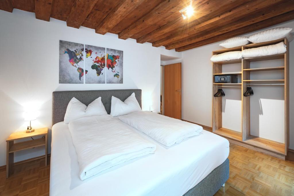 a bedroom with a large white bed and a wooden ceiling at Basic Apartments downtown in Innsbruck