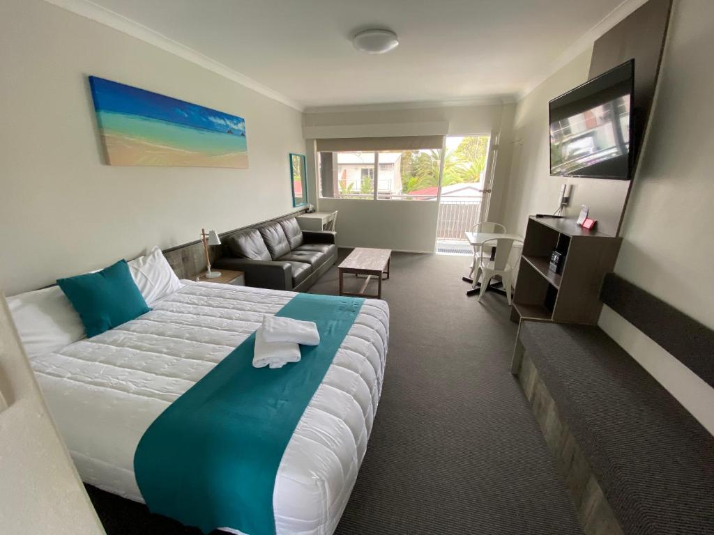 a hotel room with a large bed and a couch at Top of the Town Motor Inn in Narooma