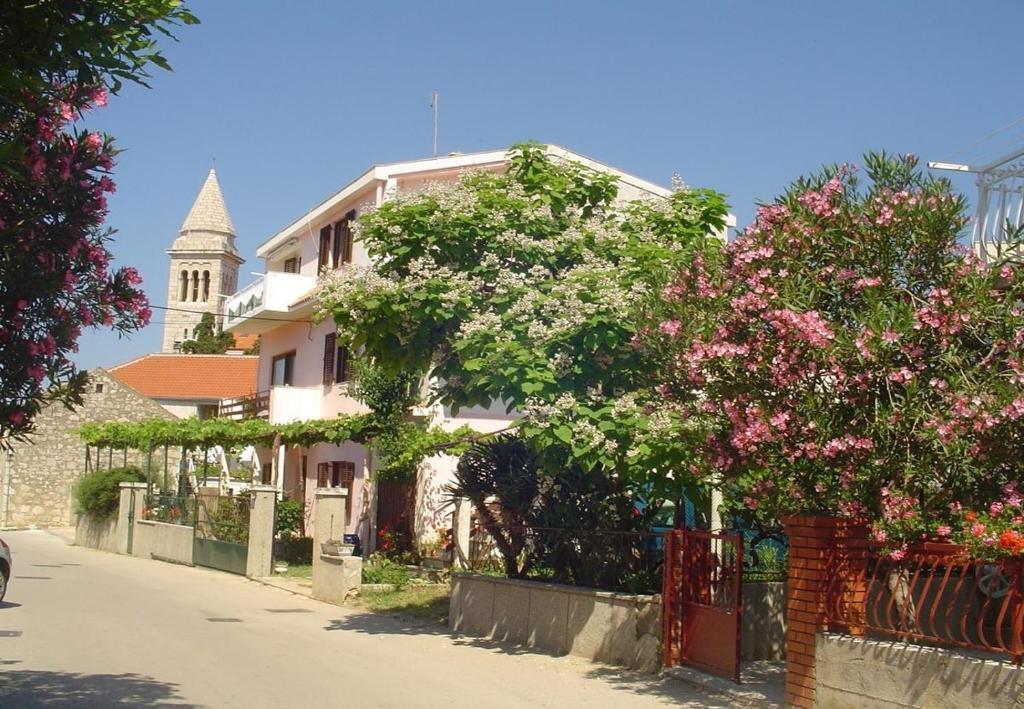 una casa bianca con un albero e un edificio con una torre di Apartments Nebo - 80 m from beach a Pakoštane