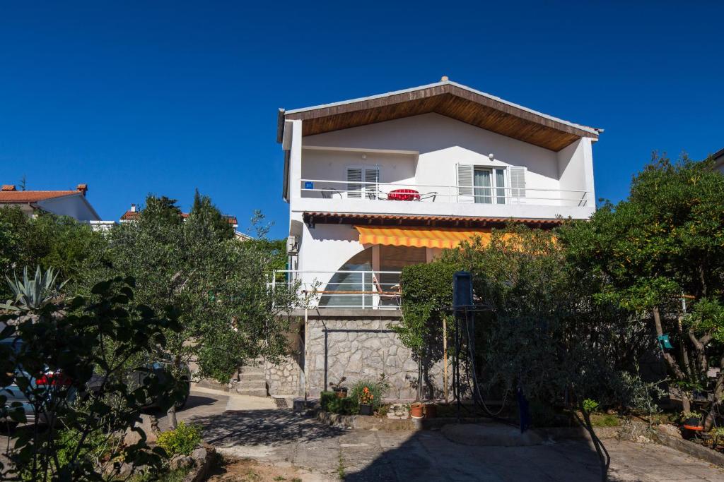 a white house with a balcony on a hill at Apartman Leana in Krk