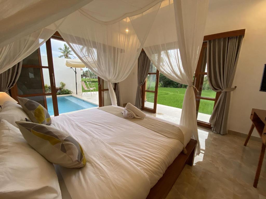 a bedroom with a white bed with a view of a pool at Luxury Villa Ada Padi Ubud one bed room in Ubud