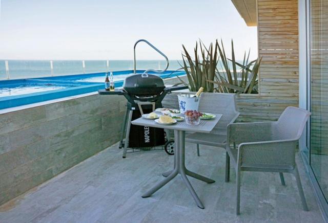 una parrilla en un patio con mesa y sillas en SYRAH Piscina Privada y Vista al Mar en Punta Ballena, en Punta del Este