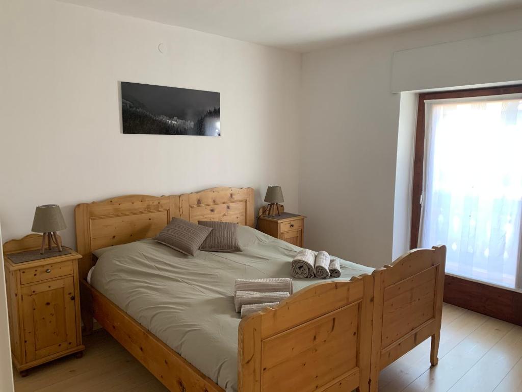 1 dormitorio con cama de madera y ventana en Appartamento Corte del Tito en Castello di Fiemme