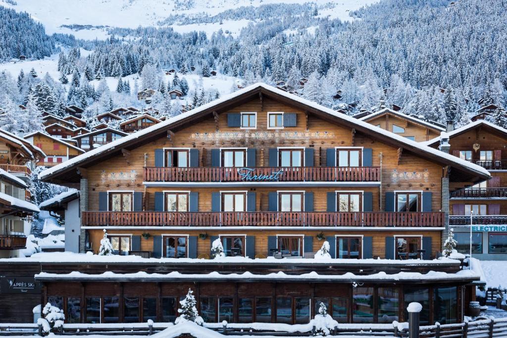 a large wooden building with snow on the roof at Hotel Farinet in Verbier