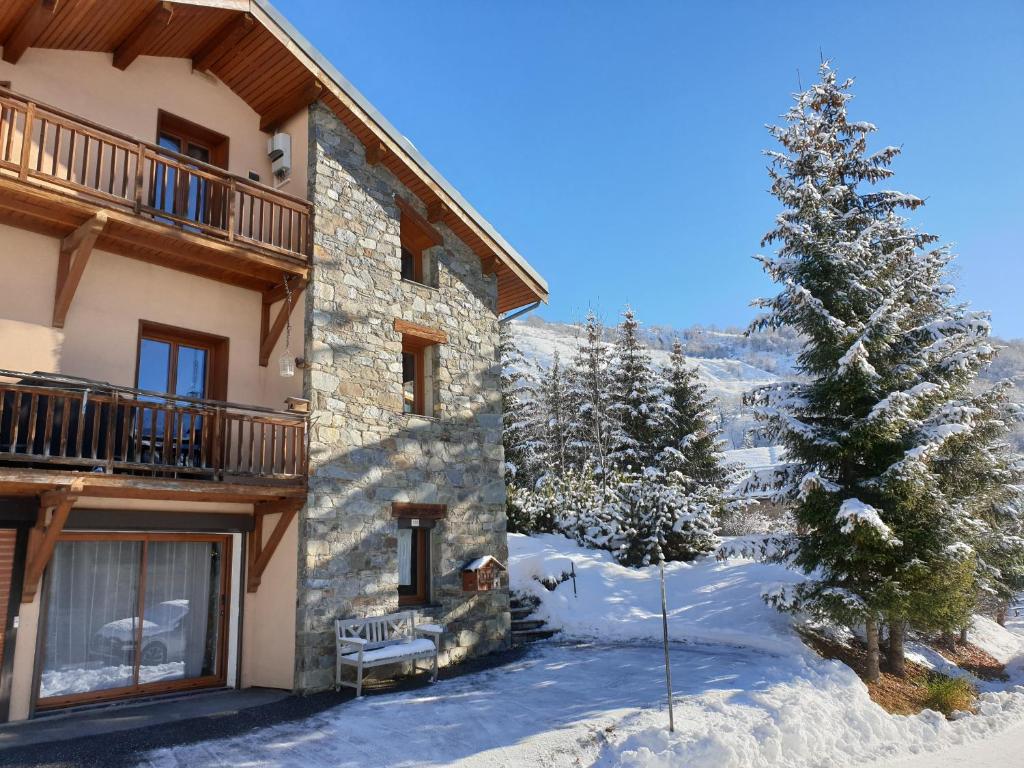 a house in the snow with a christmas tree at Chalet Coquelicot - confort montagnard et ambiance chaleureuse au cœur de Saint Martin de Belleville in Saint-Martin-de-Belleville