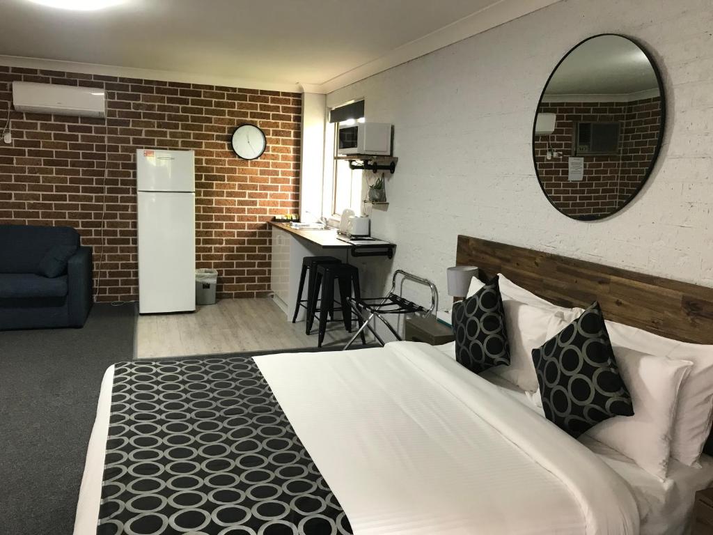a bedroom with a bed and a kitchen and a mirror at Coffs Shearwater Motel in Coffs Harbour
