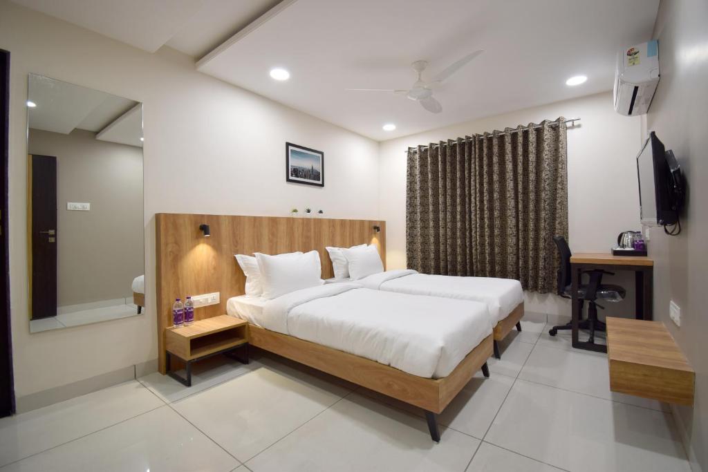 a bedroom with a bed and a desk and a television at Hotel Blue Bells in Indore