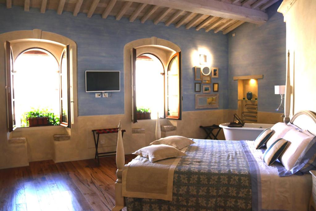 a bedroom with a bed with two windows and a television at Il Mastio di Spedaletto in Pienza