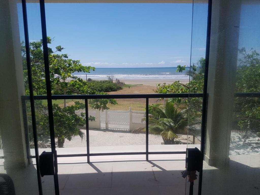 um quarto com vista para a praia a partir de uma janela em AbeQuar apartamentos beira-mar para temporada em Itanhaém