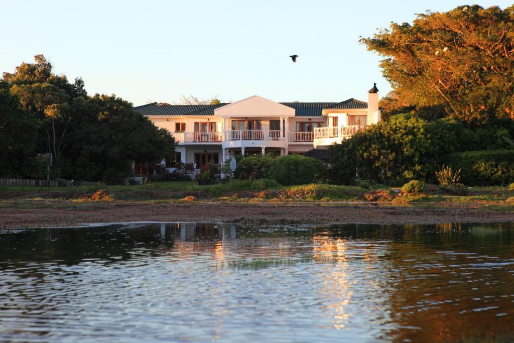 een groot huis aan de oever van een waterlichaam bij Waterfront Lodge in Knysna