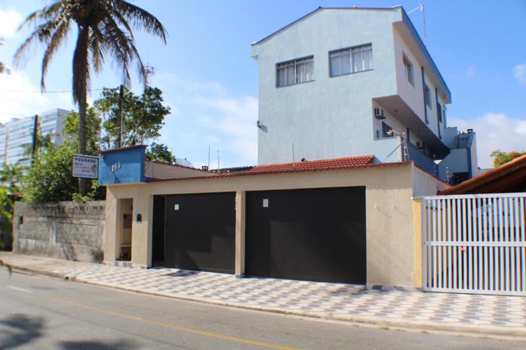 a building with four garage doors on a street at Pousada Flor de Aurora Bertioga in Bertioga