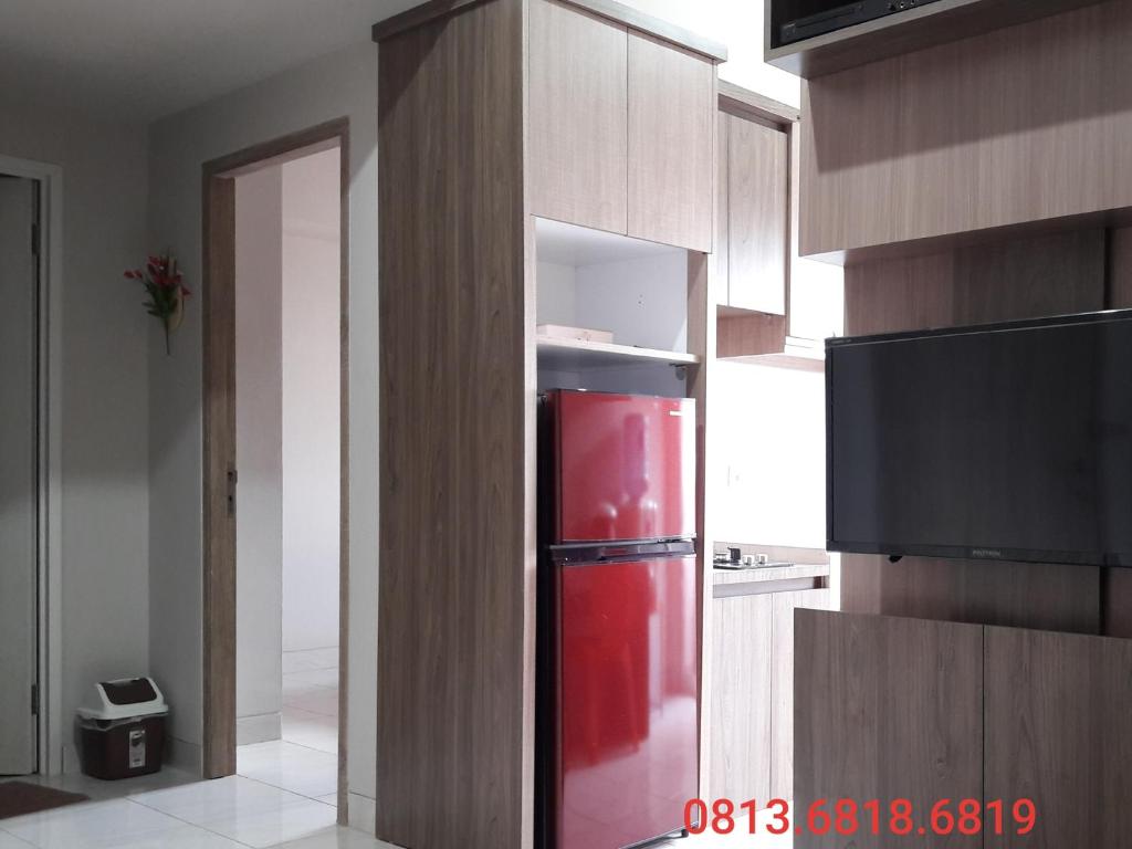 a kitchen with a red refrigerator in a cabinet at Apartemen Newton Kayla in Bandung