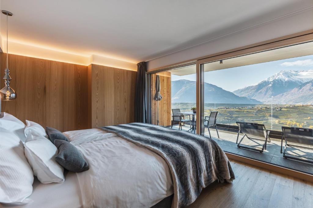 - une chambre avec un lit et une grande fenêtre dans l'établissement Dornsberg Panoramic Apartments, à Schenna