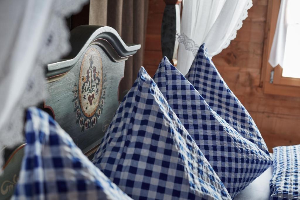 a room with blue and white checked pillows and a window at Nostalgie Bed & Breakfast Chrämerhus in Curaglia