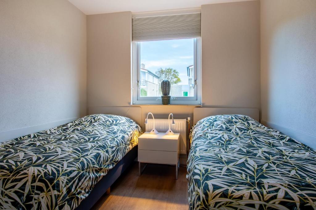 a small room with two beds and a window at Ostreahof Gezin & Familie vakantiehuis aan strand en jachthaven in Kamperland