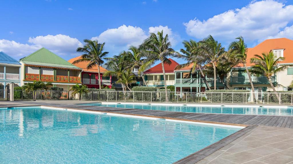 - une piscine dans un complexe avec des palmiers dans l'établissement Sea Front Apartment Orient Bay, à Baie-Orientale de Saint-Martin