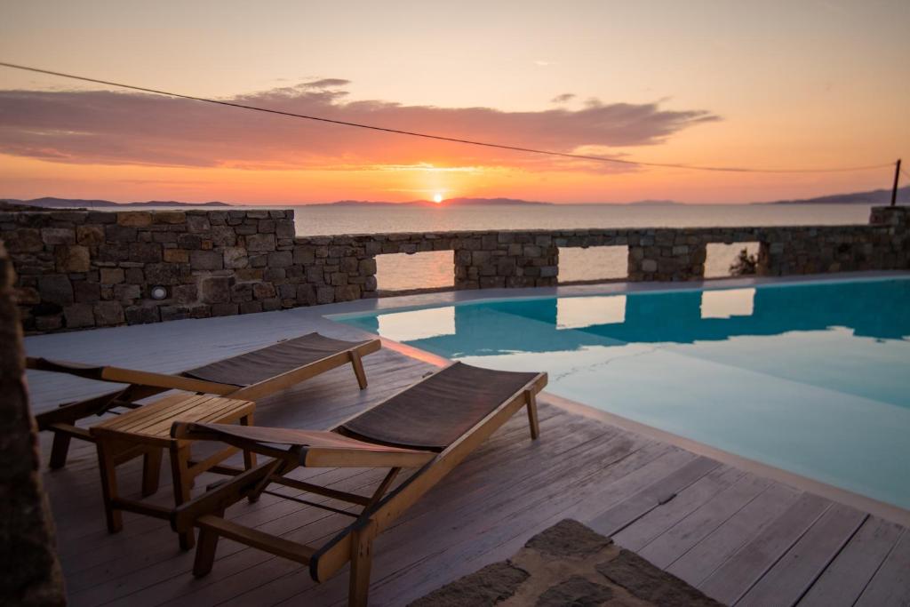 a swimming pool with a sunset in the background at Villa Choulakia in Mýkonos City