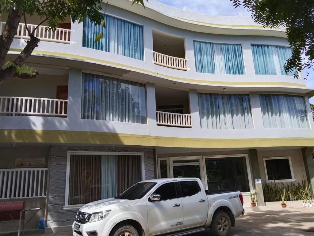 um camião branco estacionado em frente a um edifício em Sandscape Hotel em Ilha de Bantayan