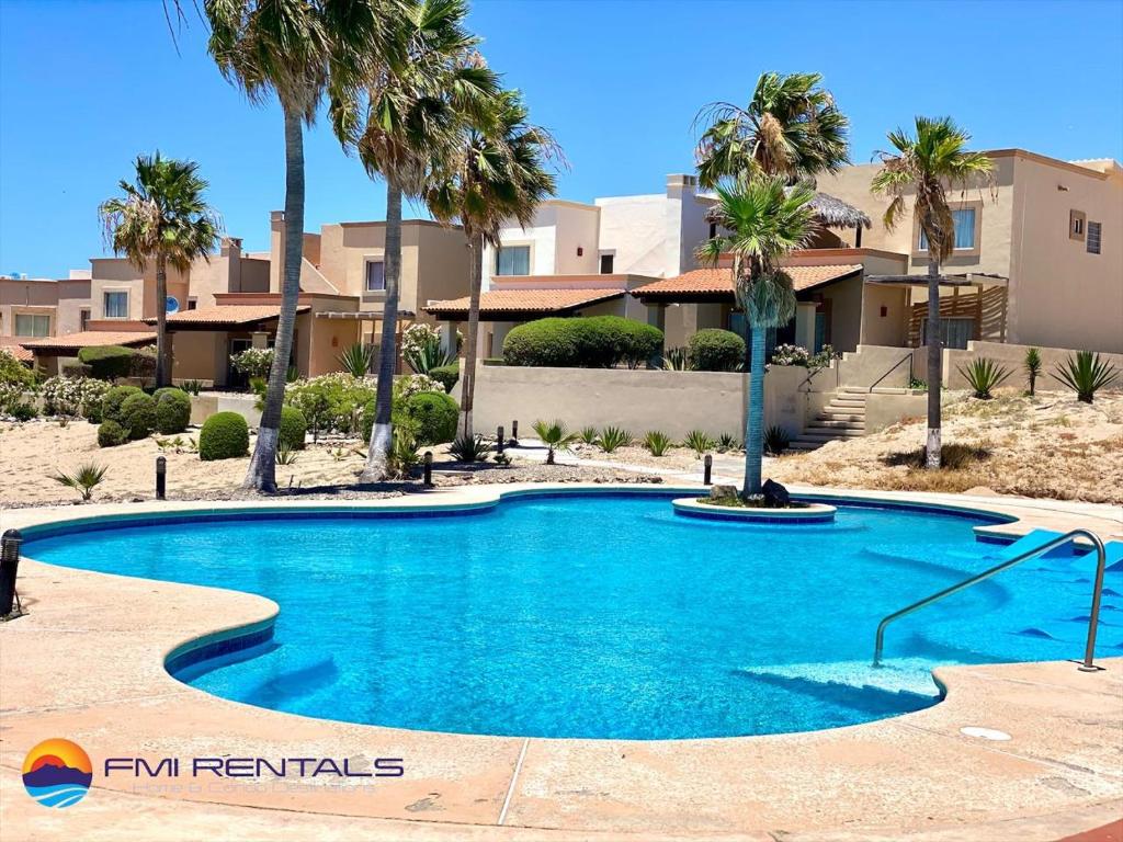 a swimming pool in front of a house with palm trees at Villa 14 in Puerto Peñasco