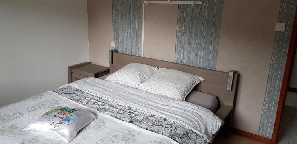 Una cama con sábanas blancas y almohadas en un dormitorio en Maison Cancela, en Siguer