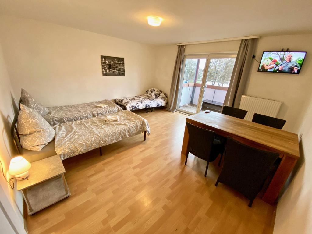 a living room with a bed and a desk and a table at Gemütliches WG-Zimmer 4, zentral in Ravensburg (stadtnah), Balkon in Ravensburg