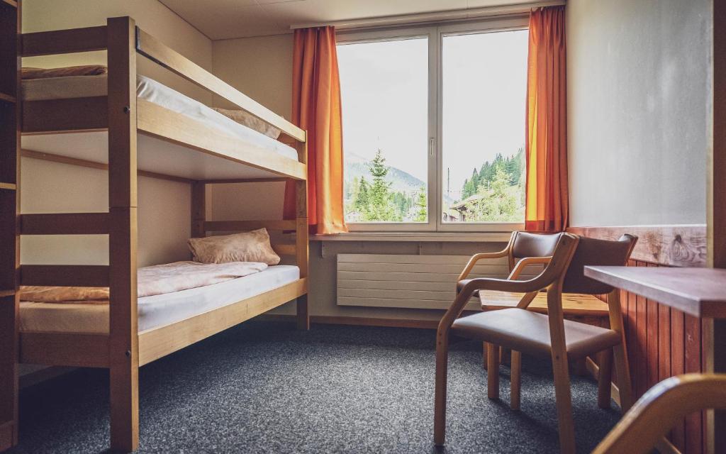 um quarto com um beliche, uma secretária e uma janela em Maxon Pavillon by Mountain Hotels em Davos