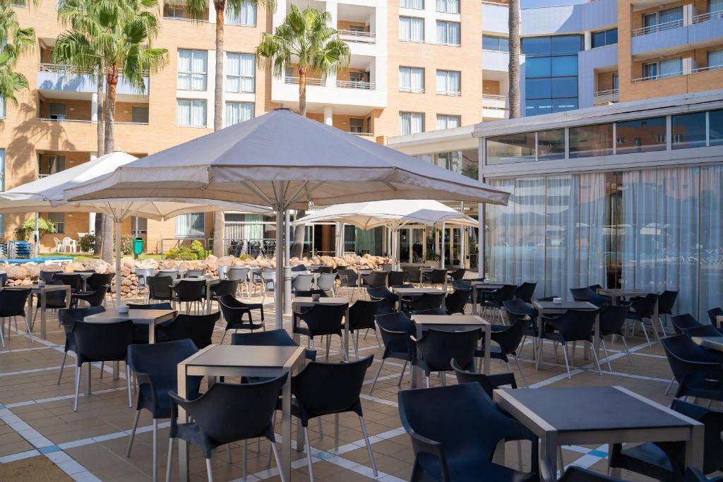 taras ze stołami, krzesłami i parasolem w obiekcie Hotel Neptuno by ON Hotels Group w mieście Roquetas de Mar