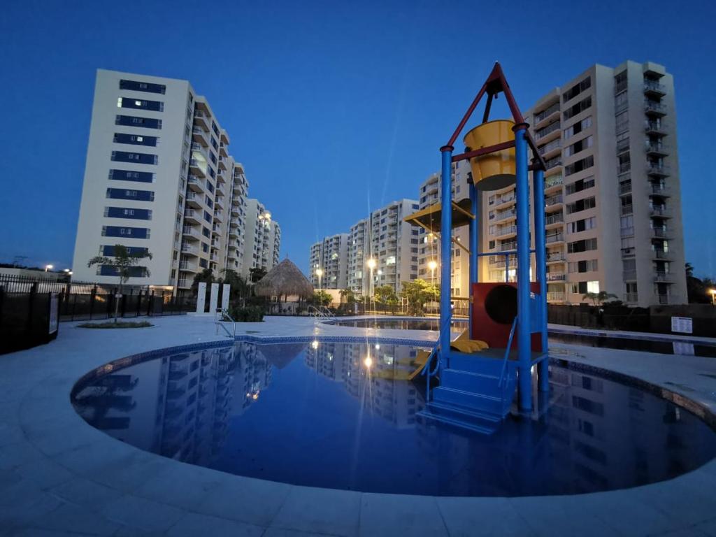 a playground in the middle of a pool with buildings at Apartamento nuevo - Amoblado en Puerto azul - Club House Piscina, Futbol, Jacuzzi, Voley playa in Ricaurte
