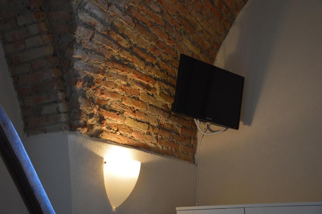 telewizor na ścianie obok ceglanej ściany w obiekcie Dimora Sole Raggiante w mieście Venosa