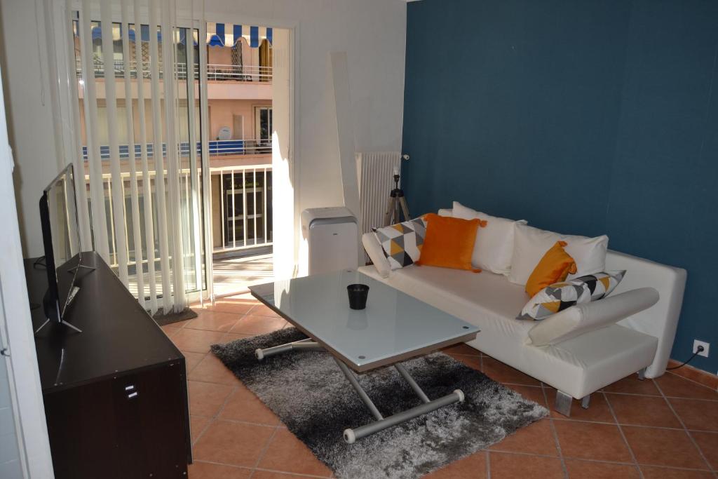 ein Wohnzimmer mit einem weißen Sofa und einem Tisch in der Unterkunft SCI LA FORGE in Antibes